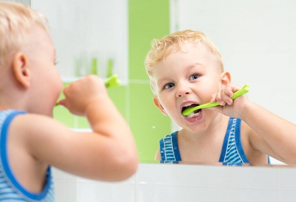 An Adorable Naughty Kid Brushing His Teeth Infront Of The Mirror.