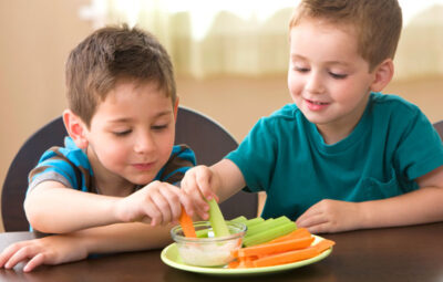Two Little Kids Eating Healthy Vegetables Representing The Healthy Teeth Concept.