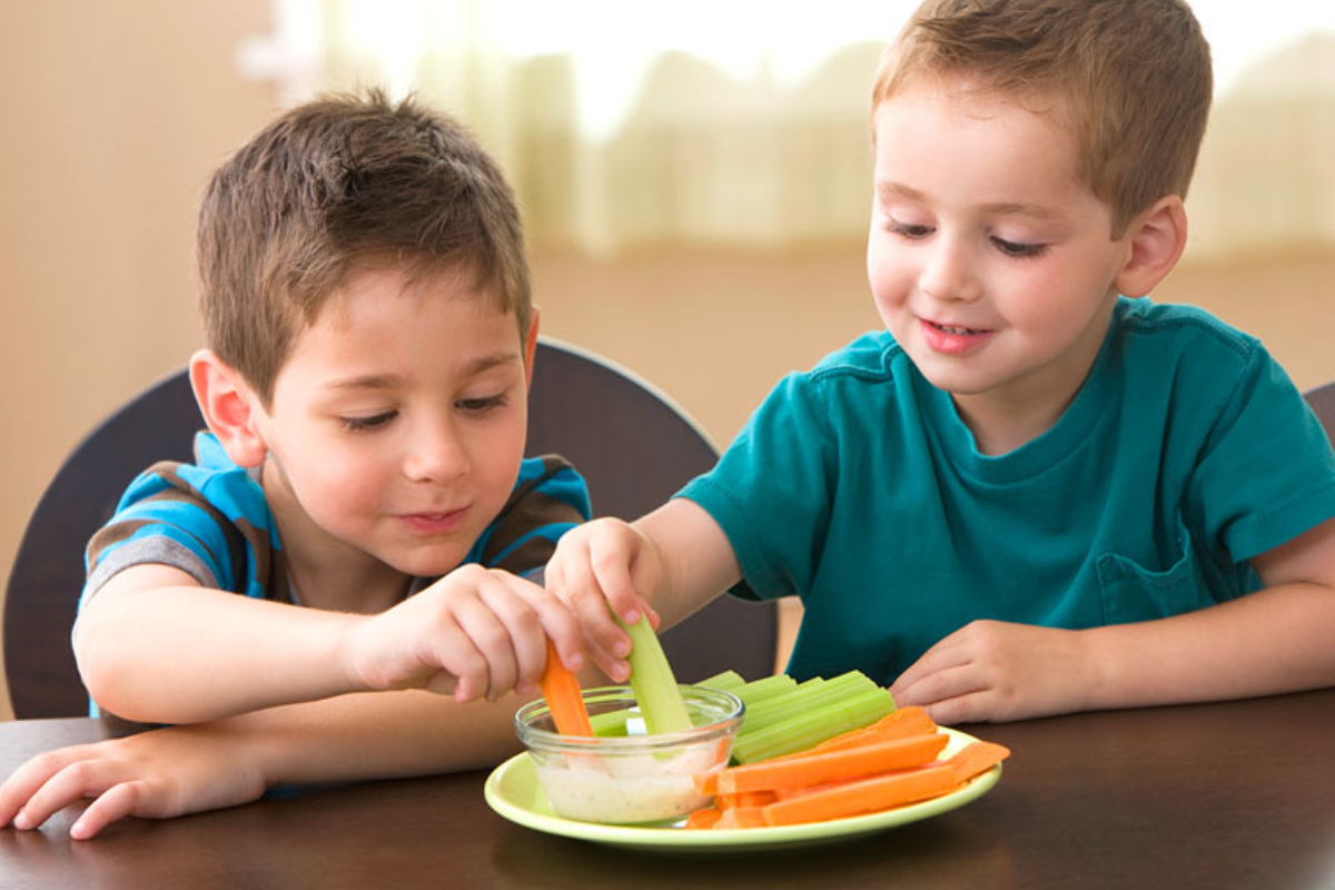 Two Little Kids Eating Healthy Vegetables Representing The Healthy Teeth Concept.
